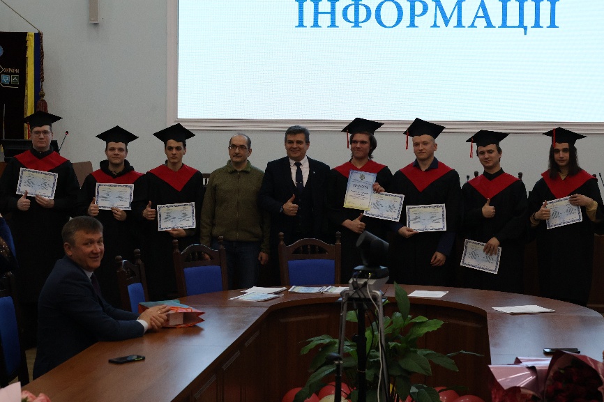 A group of people standing in front of a table</p>
<p>AI-generated content may be incorrect.