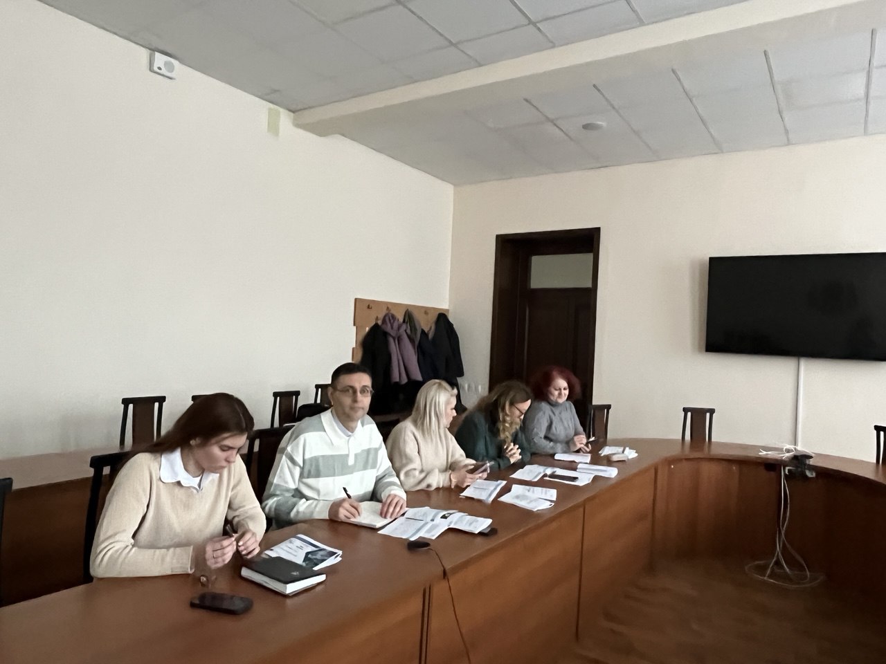 A group of people sitting at a long table</p>
<p>AI-generated content may be incorrect.