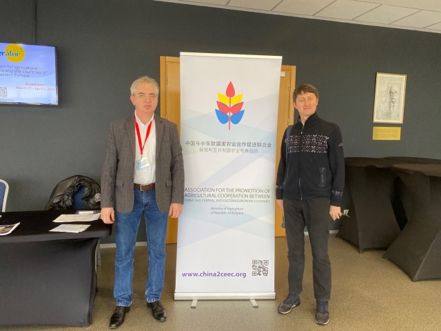 A couple of men standing next to a signDescription automatically generated with low confidence